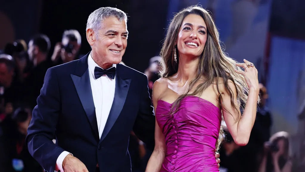 Amal Clooney wearing a stunning fuchsia high-low gown with Cartier jewelry at the 82nd Venice Film Festival red carpet