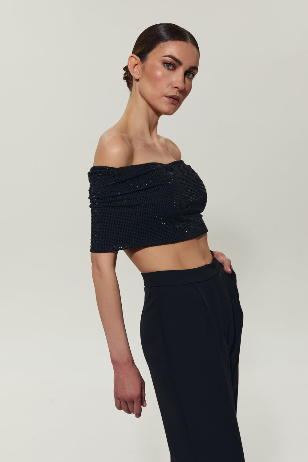 A black top with open shoulders decorated with crystals.