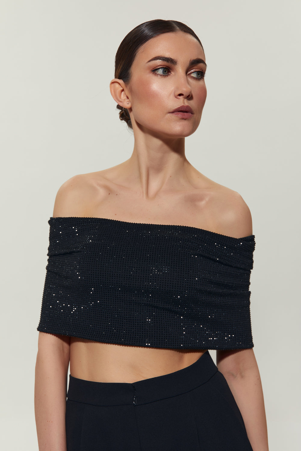 A black top with open shoulders decorated with crystals.