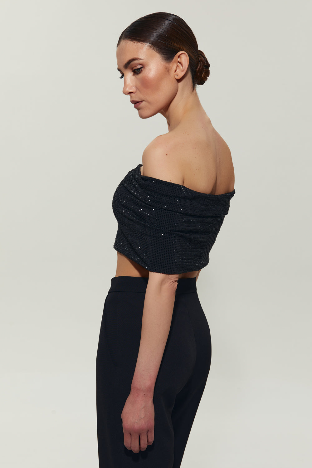 A black top with open shoulders decorated with crystals.